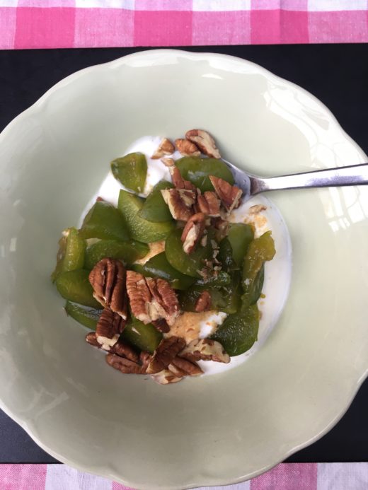 A bowl of yoghurt, pecans and greengage for breakfast.
